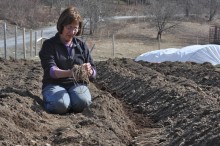 Woman smiling down whilst holding dirt